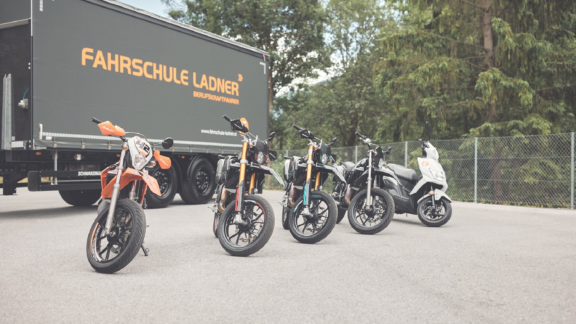 verschiedene mopeds stehen auf dem übungsplatz vor dem lkw